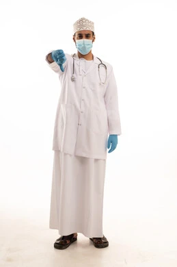 تعابير الرفض وعدم الموافقة، اتباع اجراءات السلامة للوقاية من فايروس كورونا،  بورتريه لطبيب عربي خليجي عماني يرتدي الدشداشة والعمامة والمعطف الطبي و الكمامة يضع السماعة الطبية يعمل في القطاع الصحي، الجسم بالطول الكامل، خلفية بيضاء