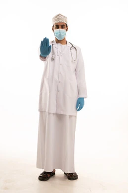 تعابير التوقف عن فعل شئ ما، اتباع اجراءات السلامة للوقاية من فايروس كورونا،  بورتريه لطبيب عربي خليجي عماني يرتدي الدشداشة والعمامة والمعطف الطبي و الكمامة يضع السماعة الطبية يعمل في القطاع الصحي، الجسم بالطول الكامل، خلفية بيضاء