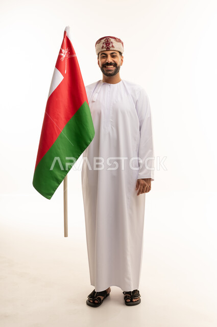 رجل عماني يحمل علم عمان على خلفية بيضاء