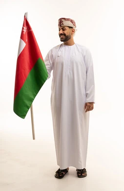 رجل عماني بالزي التقليدي يحمل علم سلطنة عمان