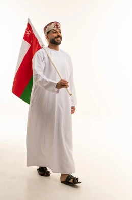 رجل عُماني يمشي حاملاً علم سلطنة عُمان