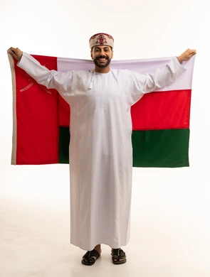 رجل عماني يحمل العلم الوطني بالزي التقليدي
