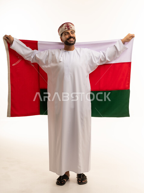 رجل عماني بالزي التقليدي يرفع علم سلطنة عمان