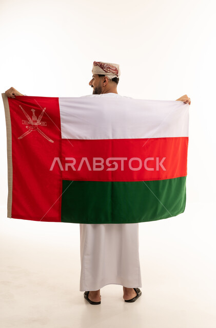 رجل عماني يحمل العلم الوطني بالزي التقليدي