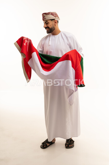 رجل عماني بالزي التقليدي يحمل علم سلطنة عمان