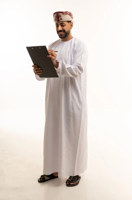 رجل عُماني بالزي التقليدي يكتب على لوحة ملاحظات