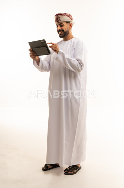 Omani Man in Traditional Dishdasha Using Tablet