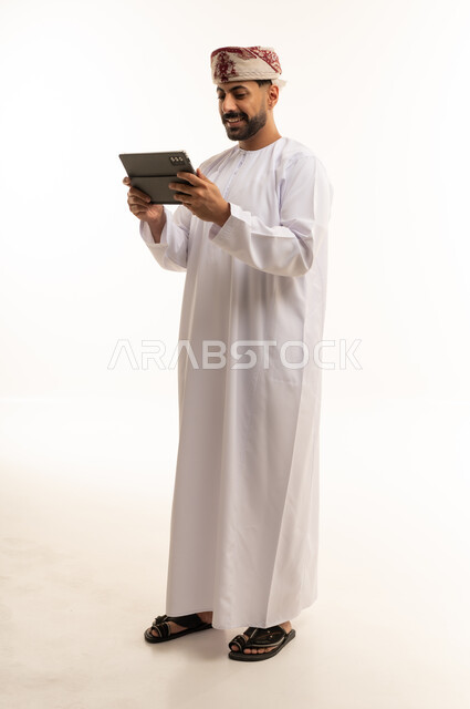 رجل عماني بالزي التقليدي يستخدم جهاز لوحي