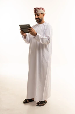 Omani Man in Traditional Dishdasha Using Tablet