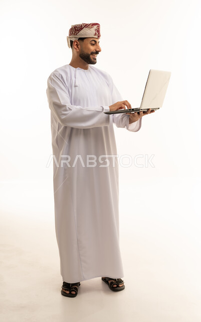رجل عماني يستخدم الكمبيوتر المحمول بالدشداشة التقليدية