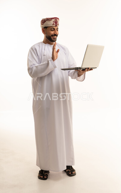 رجل عماني يحمل كمبيوتر محمول يلوح بيده خلفية بيضاء