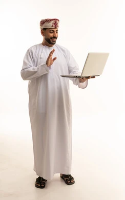 رجل عماني بالزي التقليدي يستخدم كمبيوتر محمول