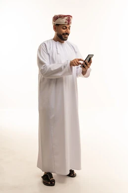 رجل عُماني بالزي التقليدي يستخدم الهاتف الذكي