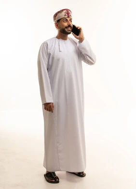 Omani Man in Traditional Dishdasha Using Smartphone