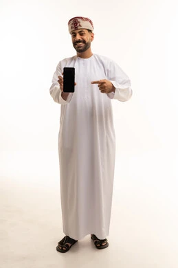 رجل عُماني بالزي التقليدي يشير إلى هاتف ذكي