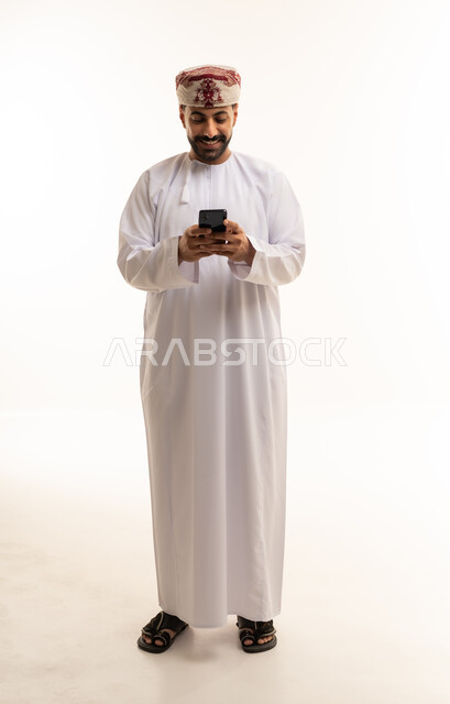 Omani Man Using Smartphone in Traditional White Dishdasha
