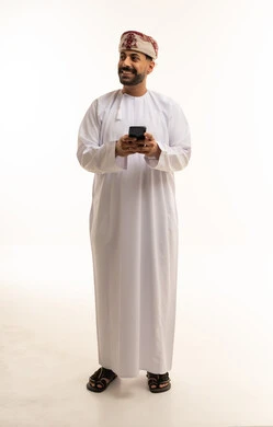 Omani Man in Traditional Dishdasha Using Smartphone