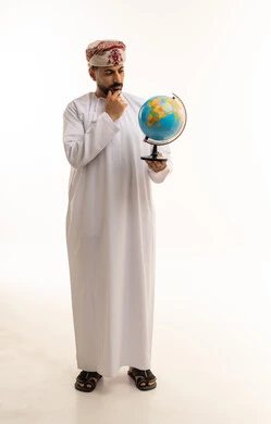 رجل عماني بالزي التقليدي ينظر إلى مجسم الكرة الأرضية
