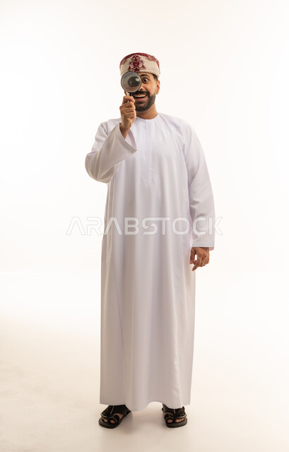 رجل عماني بالزي التقليدي يستخدم عدسة مكبرة