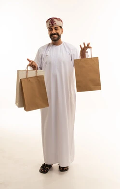 رجل عماني بزي تقليدي يحمل أكياس تسوق