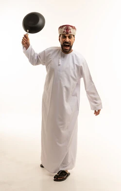 رجل عماني بالزي التقليدي يصرخ ويمسك بمقلاة