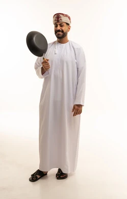 رجل عُماني يحمل مقلاة بالزي التقليدي العماني