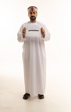 رجل عماني يحمل لوحة ساعدني على خلفية بيضاء