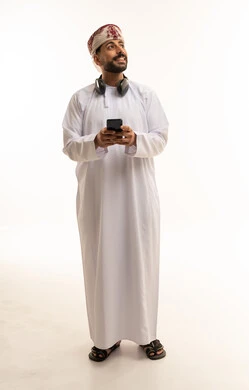 رجل عُماني بالزي التقليدي يستخدم الهاتف الذكي