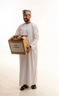 رجل عماني يحمل صندوق تبرعات طعام خلفية بيضاء