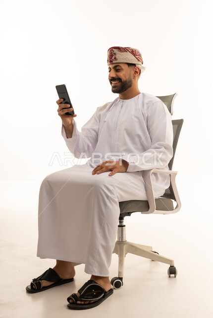 رجل عماني بالزي التقليدي يستخدم الهاتف الذكي