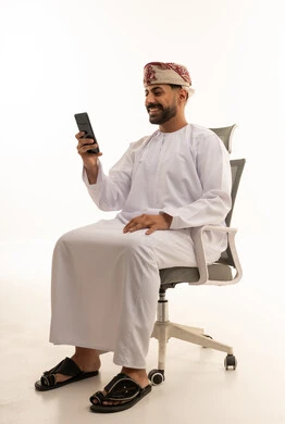 رجل عماني بالزي التقليدي يستخدم الهاتف الذكي
