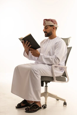 رجل عماني بالزي التقليدي يقرأ كتاباً