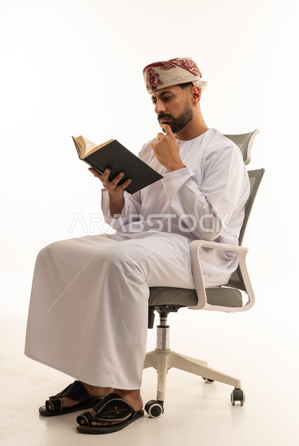 Omani Man in Traditional Dress Reading Book in Studio
