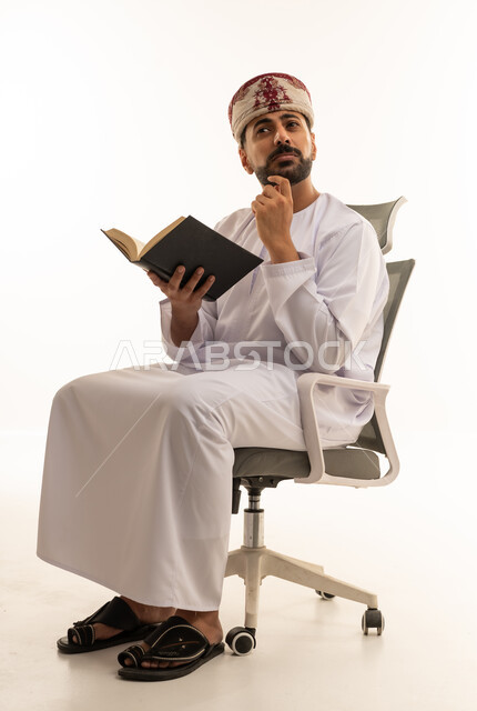 رجل عُماني بالزي التقليدي يقرأ كتاب