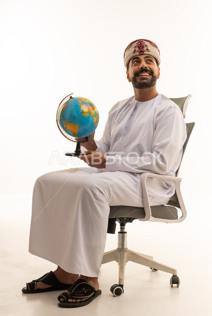 رجل عماني بالزي التقليدي يمسك مجسم الكرة الأرضية