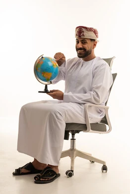 رجل عماني بالزي التقليدي يشير إلى مجسم الكرة الأرضية