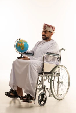 رجل عماني على كرسي متحرك يمسك بمجسم الكرة الأرضية