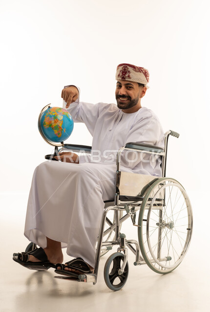 رجل عُماني على كرسي متحرك يحمل الكرة الأرضية