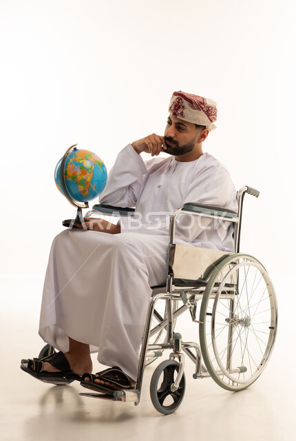 رجل عُماني على كرسي متحرك يمسك كرة أرضية