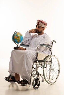 رجل عُماني على كرسي متحرك يمسك كرة أرضية
