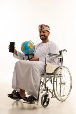 رجل عماني على كرسي متحرك يحمل مجسم الكرة الأرضية