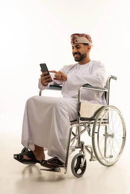 رجل عماني على كرسي متحرك يستخدم الهاتف