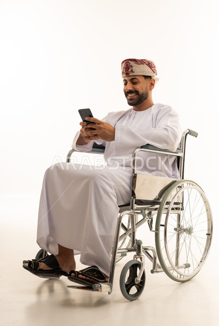 رجل عُماني على كرسي متحرك يستخدم الهاتف الذكي