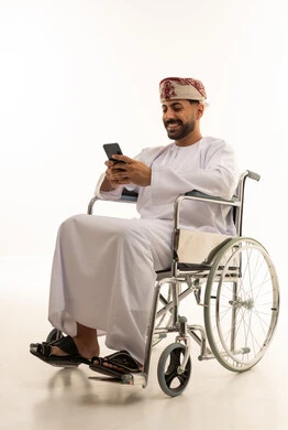 رجل عُماني على كرسي متحرك يستخدم الهاتف الذكي