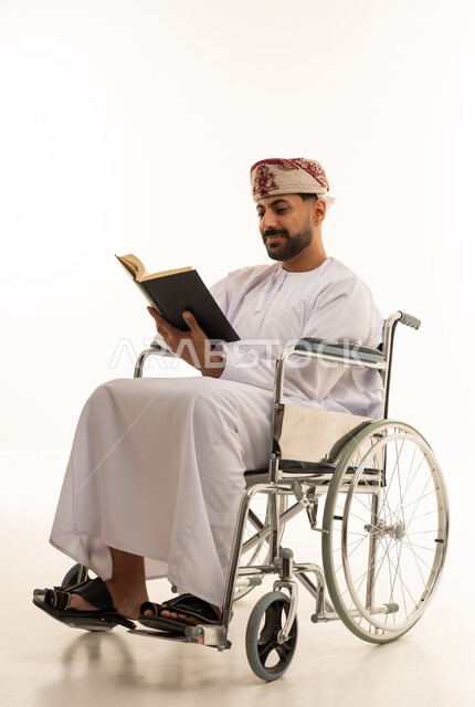 رجل عماني على كرسي متحرك يقرأ كتاباً