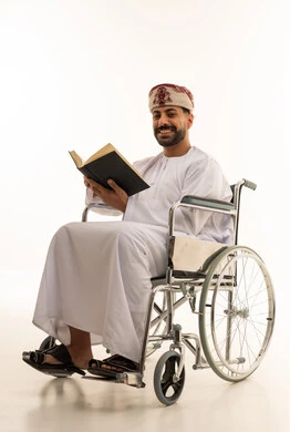 رجل عُماني على كرسي متحرك يقرأ كتاباً