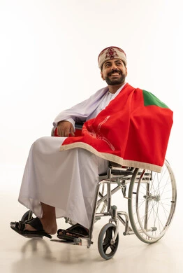 رجل عماني من ذوي الإعاقة مع العلم العماني