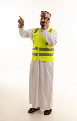 مهندس عماني يرتدي سترة السلامة يتحدث بالهاتف