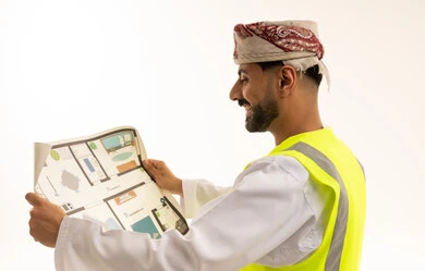 مهندس عماني يمسك مخطط بناء معماري