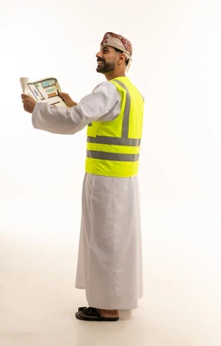 مهندس عماني بالزي التقليدي يمسك مخطط بناء